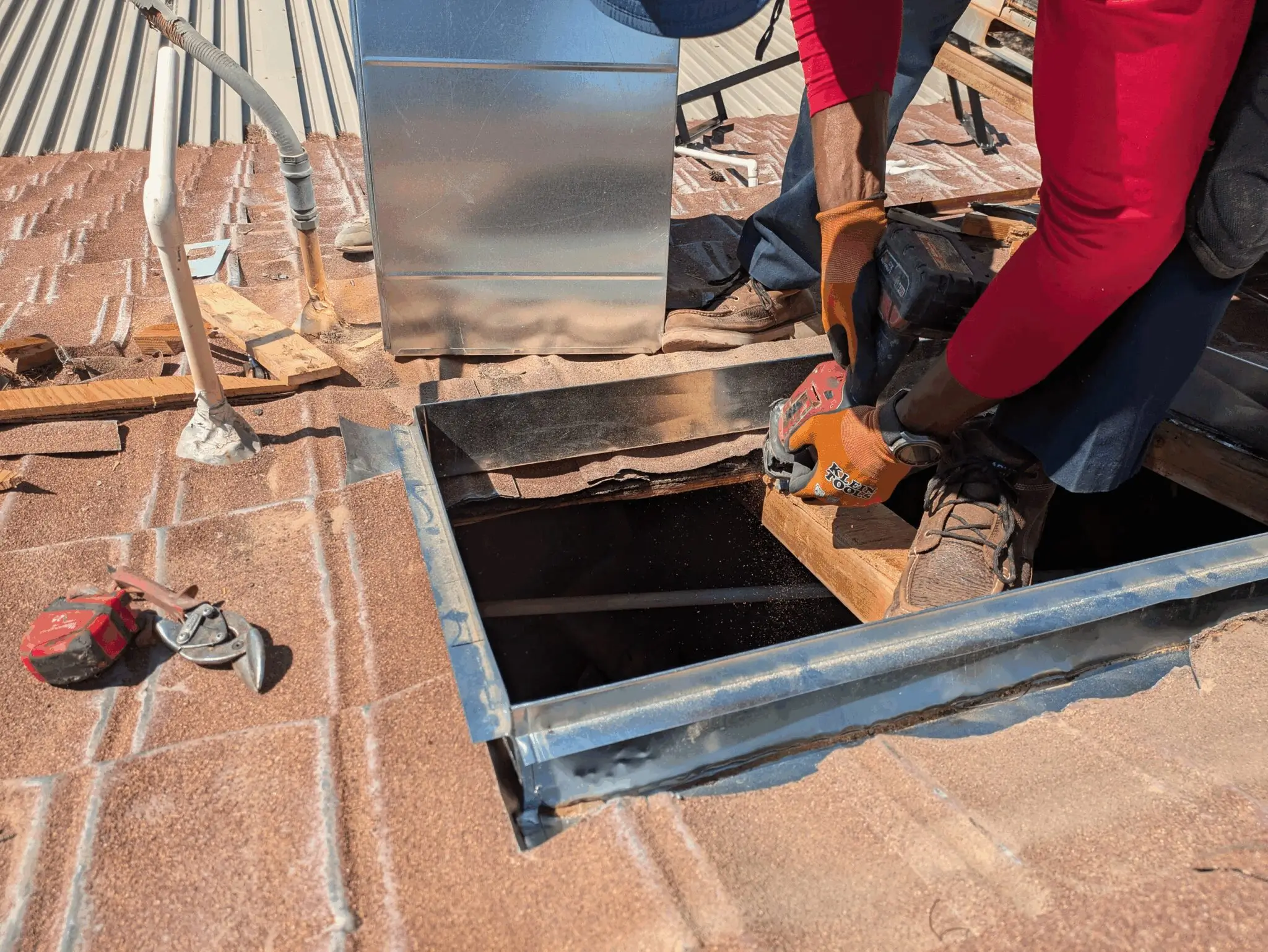 Person working on a rooftop opening a hatch to a building interior.
