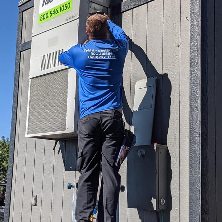 A worker installs a solar panel on a wooden wall under clear skies.